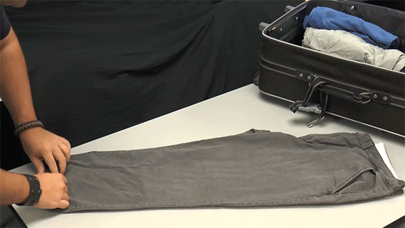 gif un homme roule ses affaires pour qu'elles prennent moins de place dans la valise